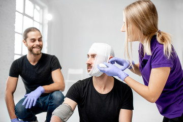 Group of young people during the first aid training with instructor showing how to tie a bandage on the head of injured person