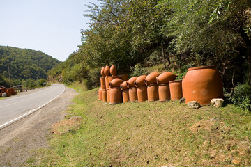 Many large earthenware jugs for wine are sold near the road.