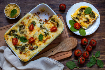 Lasagna with meat, Parmesan cheese, spinach and Béchamel sauce on wooden background