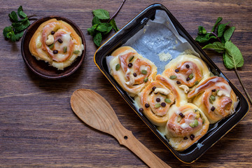 Cinnabon with cream cheese, cashews and chocolate chips on wooden background