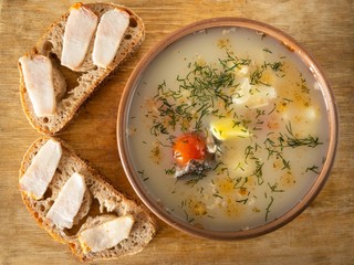 Top view on simple lunch- fish soup and two sandwiches with slices of pork