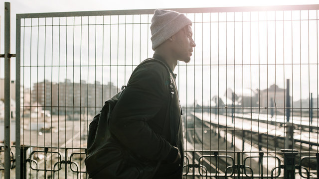 Side view of young african american man walking by the city in a sunny day of winter