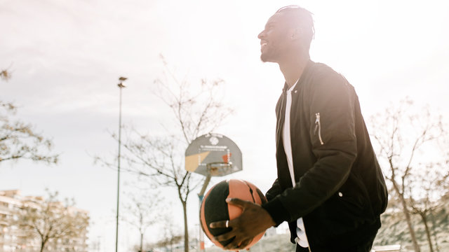 Side view of young african man throwing a ball in a basket on a basketball court