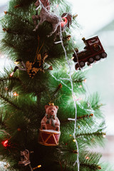 Christmas tree decorated with vintage toys, close up, fairy, bear, train, unicorn and a garland on the green background 