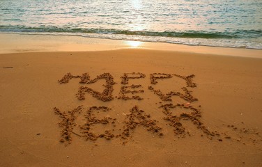 Happy new year concept handwriting on the sand beach.