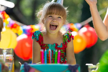 Cute schoolgirl with big happy smile during her outdoor birthday party