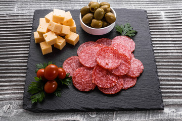 delicious sliced salami on a stone plate wooden background