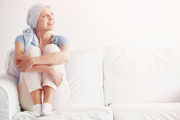 Bright photo of happy pretty girl suffering from kidney cancer, wearing blue headscarf and siting...