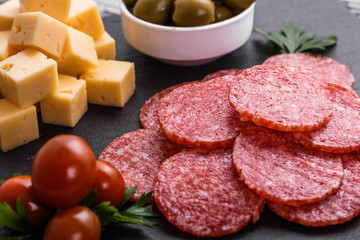 delicious sliced salami on a stone plate wooden background