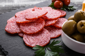 delicious sliced salami on a stone plate wooden background
