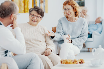 Group of elderly people at senior's club talking and laughing together during meeting