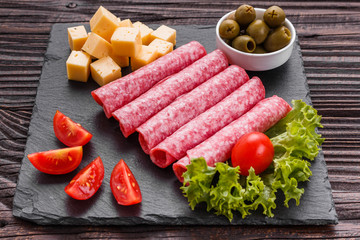 delicious sliced salami on a stone plate wooden background