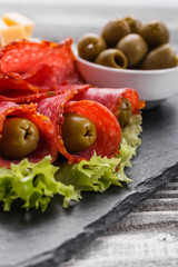 delicious sliced salami on a stone plate wooden background