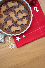 Homemade puff pastry Christmas tart with jam filling decorated with stars. Christmas festive dessert on wooden table
