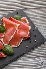 Italian prosciutto crudo or spanish jamon on a stone plate wooden background