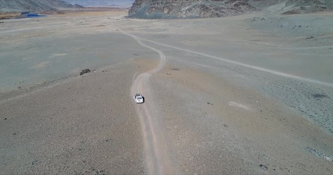 4k 60 fps Mongolia Aerial view of Altai desrt track with 4x4 driving - following from back in curve