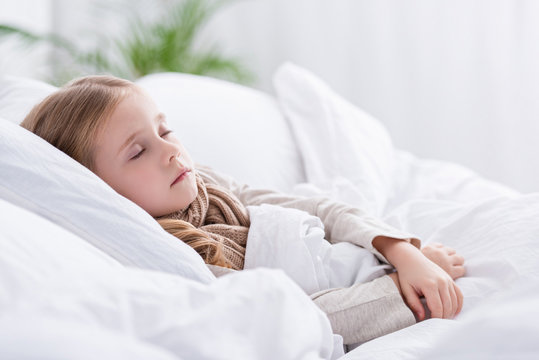 sick child with scarf over neck sleeping in bed at home