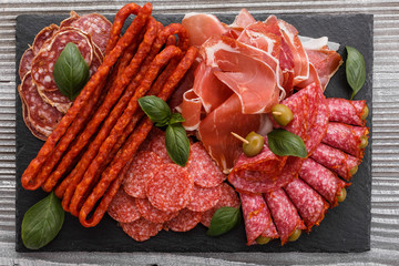 Cold smoked meat plate on a rustic wooden background