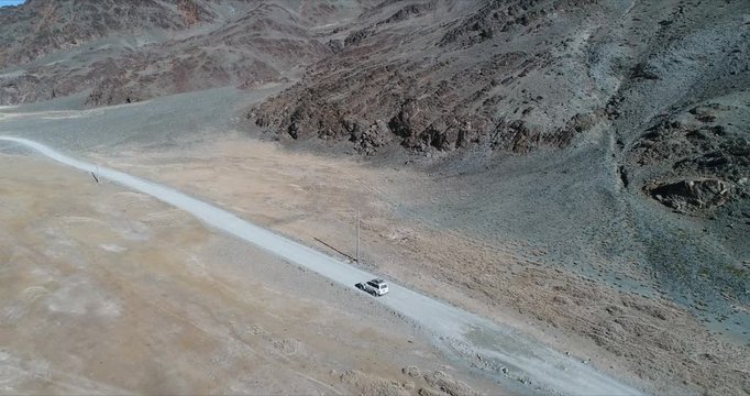 4k 60 fps Mongolia Aerial view of Altai desrt track with 4x4 driving -  along desert rock mount
