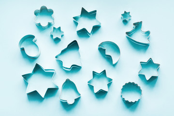 Various Christmas-themed cookie cutters on blue. Holiday card. View from above. Xmas pattern.