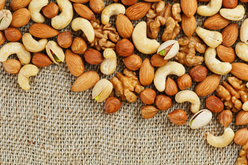 Mix of nuts lying on a background of brown cloth burlap.
