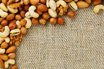 Mix of nuts lying on a background of brown cloth burlap.