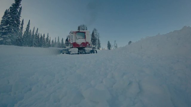 snowcat rides down the road in the mountain valley in the evening and makes a sharp turn. snow dust in the frame. 4k super quality
