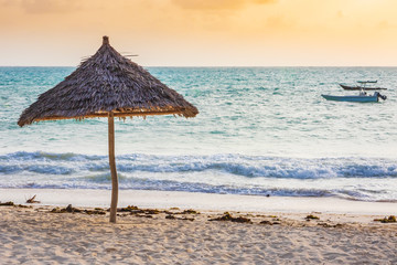 Umbrella beach equipment made of natural materials at a tropical beach during sunset