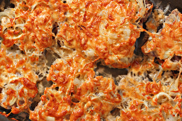 Baked meat with chopped onion and cheese on a baking tray. Food texture and background. Top view. Closeup