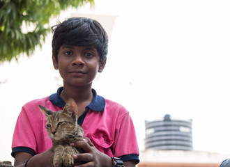 Obraz premium Young Indian boy holding kitten in his hand