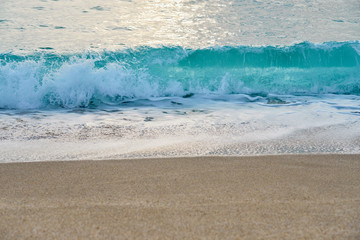 Waves with foam hitting sand on the tropical beach texture.
