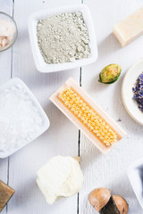 spa products: black mud and clay powder, cosmetic cream, soap, bath salt, shea butter and lavenders on white wood table background