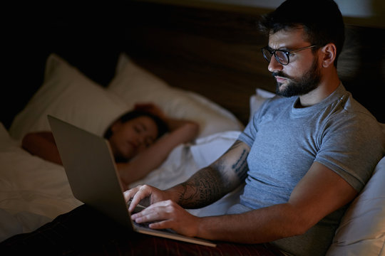 man lying on bed and working with laptop late at night..