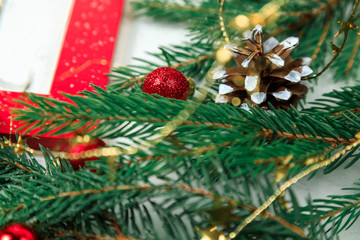 New Year's background. Christmas jewelry on fir-tree branches, gold spheres, garlands and a red frame for a photo or an inscription. White backgroun