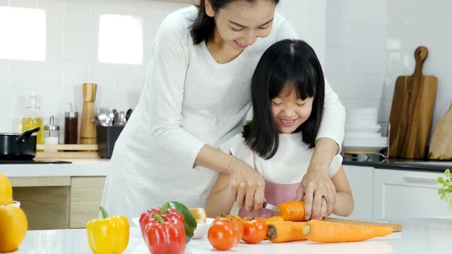 Little girl try to cooking by herself at kitchen. Mother teaching her daughter to cooking. People with lifestyle and healthy concept.