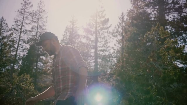 Camera follows young happy local man in checkered shirt hiking alone at beautiful Yosemite national forest slow motion.