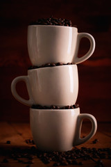 Three cup full of coffee beans on a wooden table