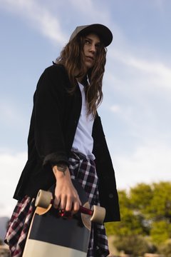 Female skateboarder standing with skateboard
