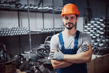 Portrait of a young worker in a hard hat at a large metalworking plant. Shiftman on the warehouse...