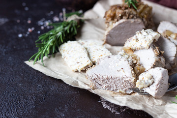 Roast pork meat with onion, garlic and rosemary served with nuts butter on brown stone table. 