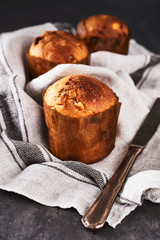 Mini Panettone with raisins and dried fruits on kitchen cloth over concrete table.