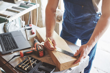 A man works in a joiner's shop, working with a tree.