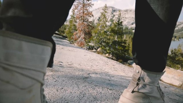 Close-up camera follows male legs in white desert shoes hiking alone at beautiful Yosemite forest rock slow motion.