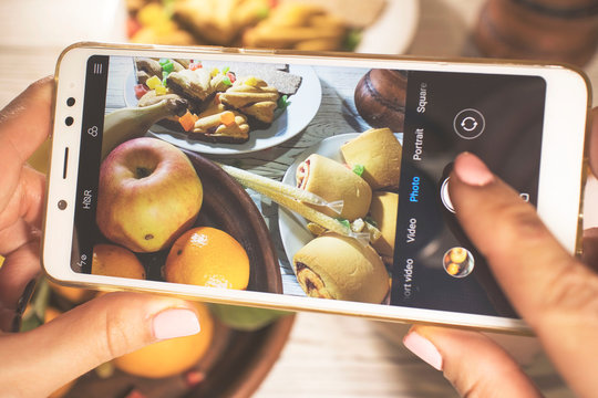 Smartphone in the hands of women, food photography, dinner on the table. apples, bananas, cookies