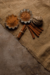 Finely chopped cinnamon and cinnamon sticks on a textured background with textiles. Top view.