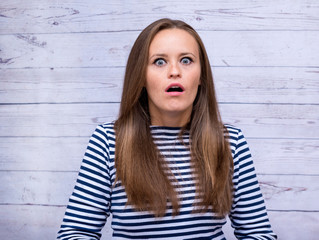 girl in a vest with long hair with a surprised frightened expression