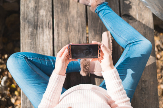 Top view of beautiful pregnant looking ultrasound image in her mobile phone.Concept of pregnancy, health care, gynecology, medicine. Young mother waiting of the baby.