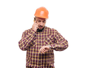 An angry and nervous worker in an orange helmet is talking loudly on the phone, shouting into the phone. Isolated white background