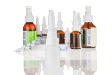 Nasal spray bottle close up and blurred drugs isolated on white background