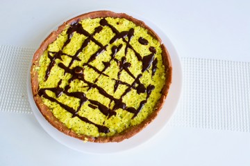 Tasty yellow lemon tart with the dark chocolate on the white table